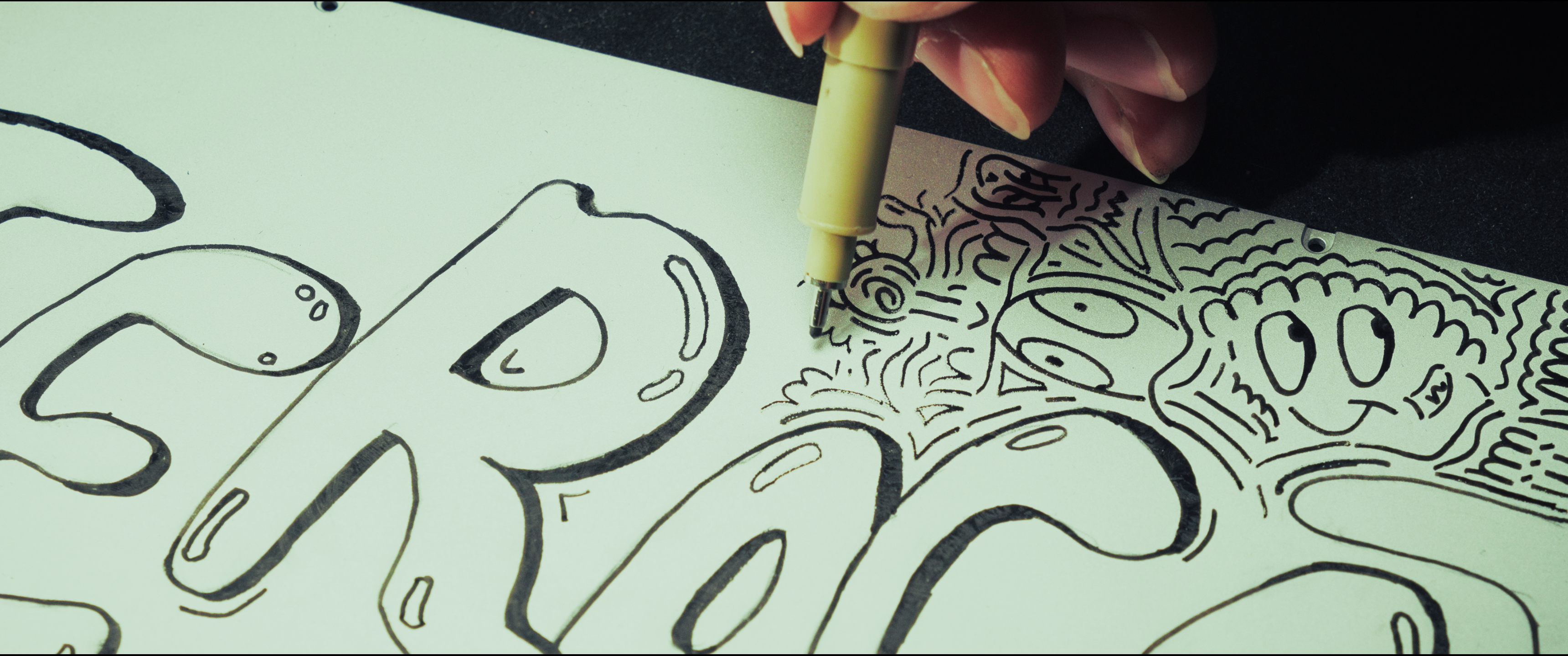 A close-up of the keyboard shell being covered with hand-drawn characters and lines